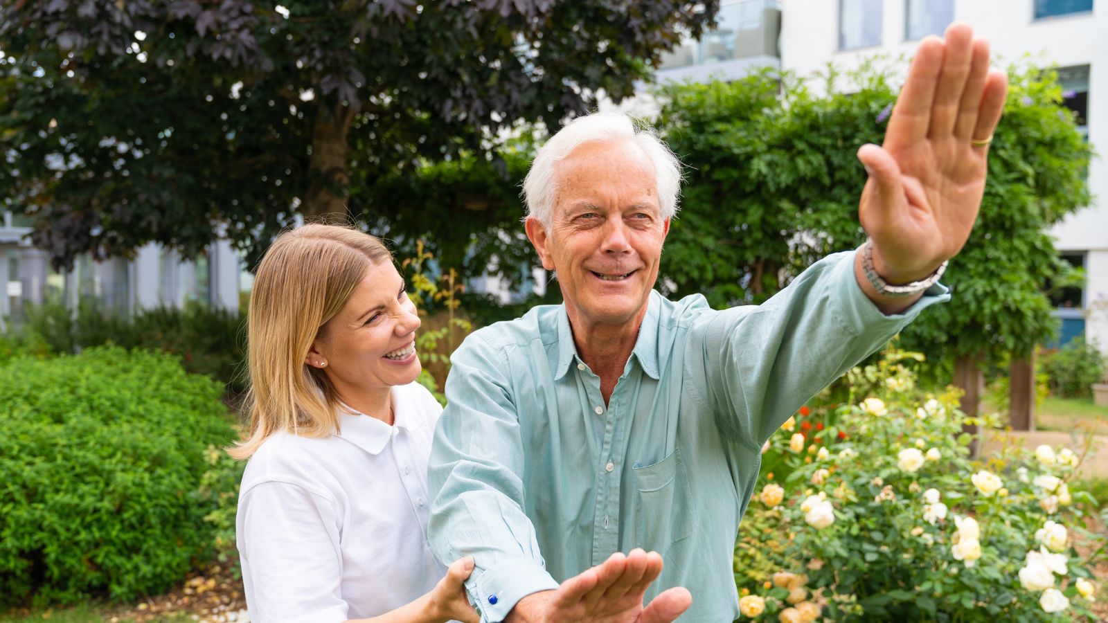 A member of staff helping a resident in the garden with exercises