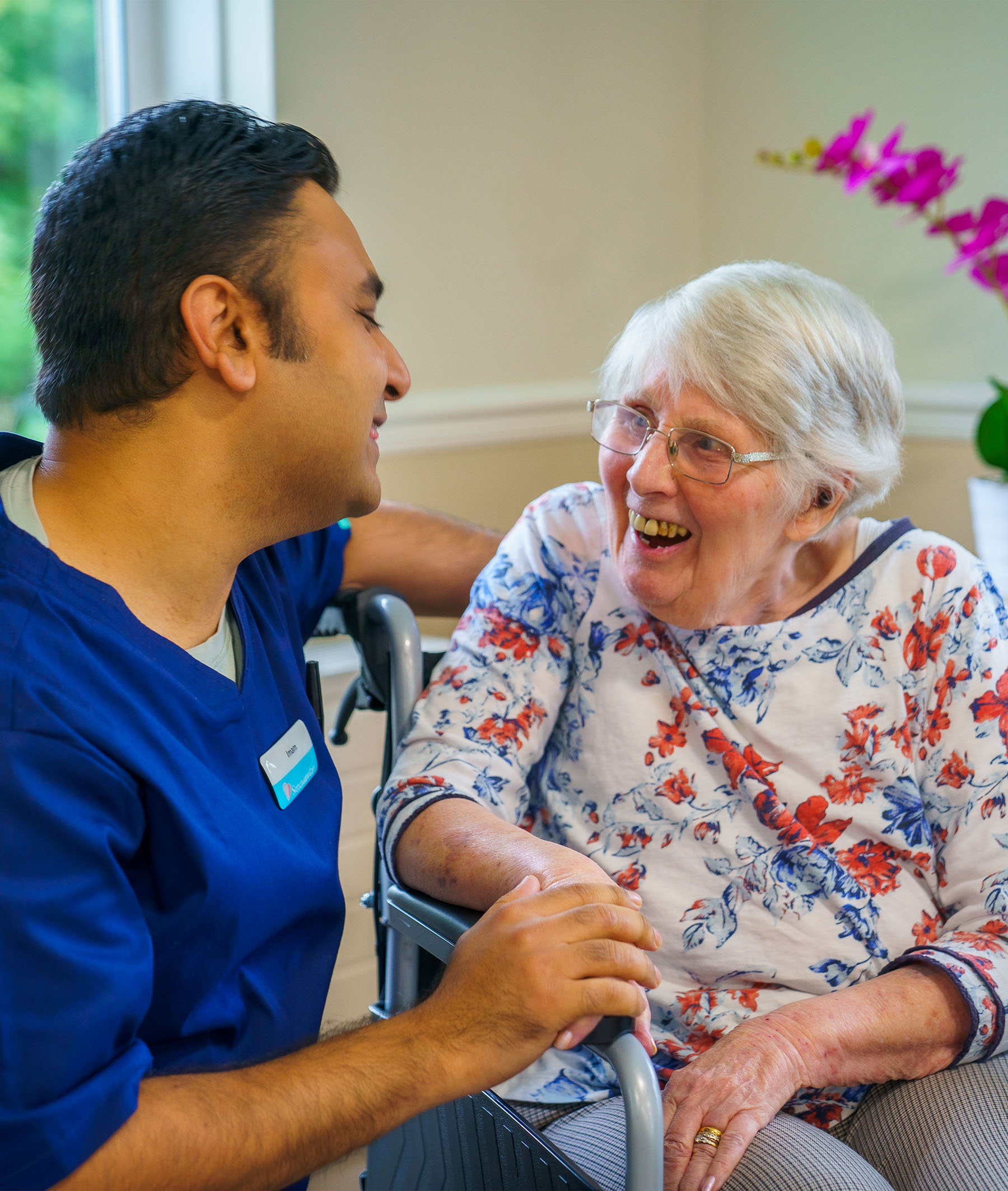 Care worker with resident in wheelchair smiling at each other